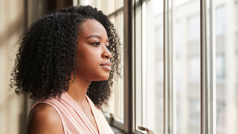 A woman gazing thoughtfully out a window, reflecting inner restlessness and contemplation - jillbosman.com