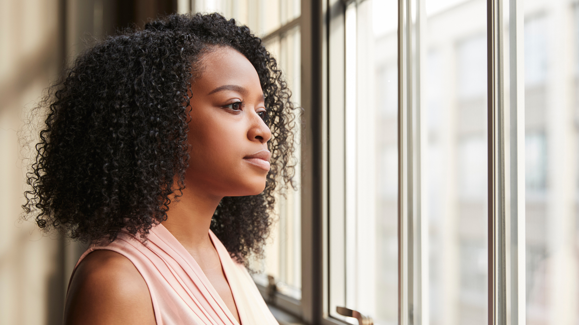 A woman gazing thoughtfully out a window, reflecting inner restlessness and contemplation - jillbosman.com